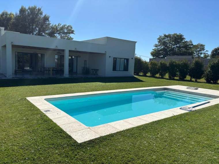 Pileta de fibra instalada en un jardín, con casa de fondo