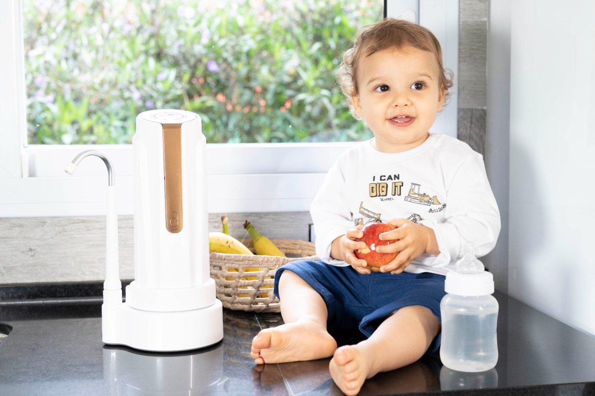 Bebé sentado en la mesada de la cocina junto a un purificador DVIGI AS PLUS