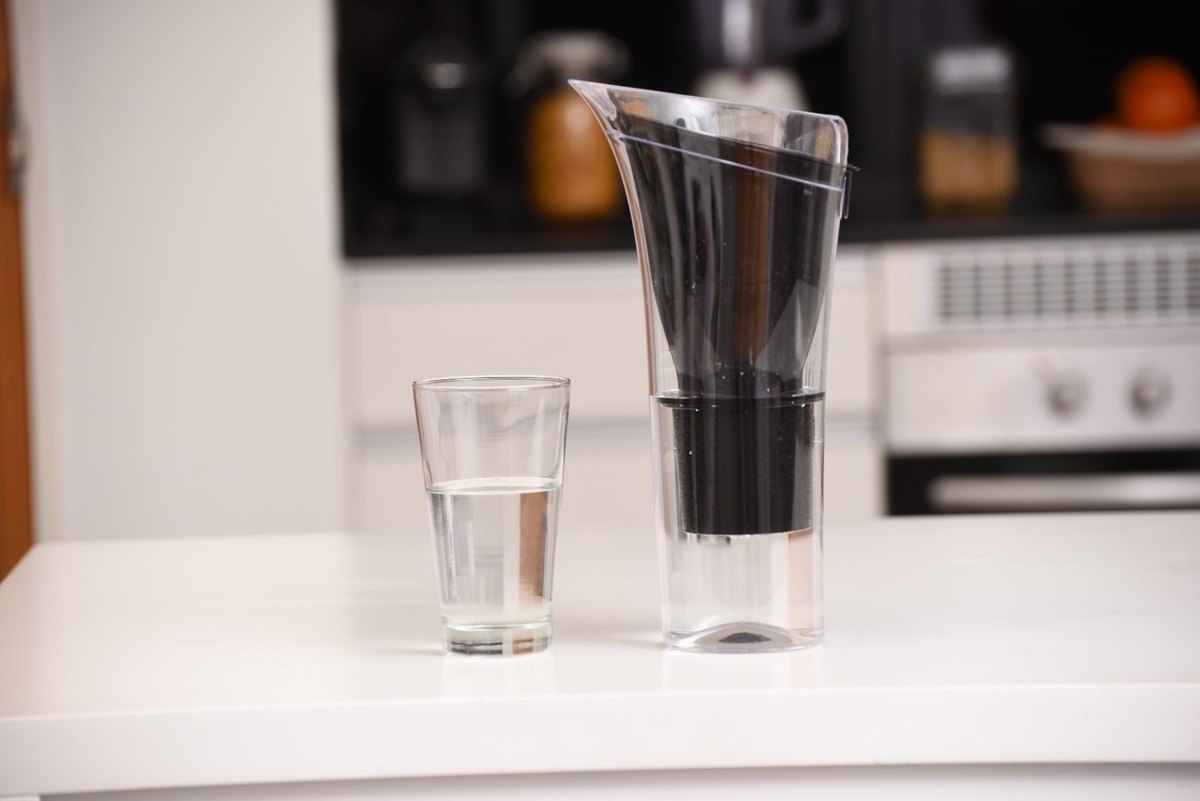 Jarra purificadora DVIGI SENSE sobre la mesada de una cocina, junto a un vaso de agua