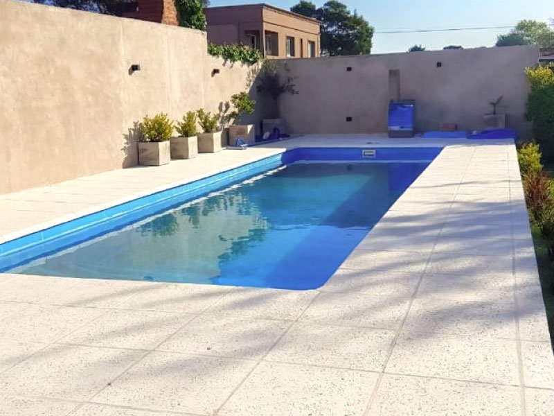 Pileta con vereda atérmica blanca alrededor, a pleno sol